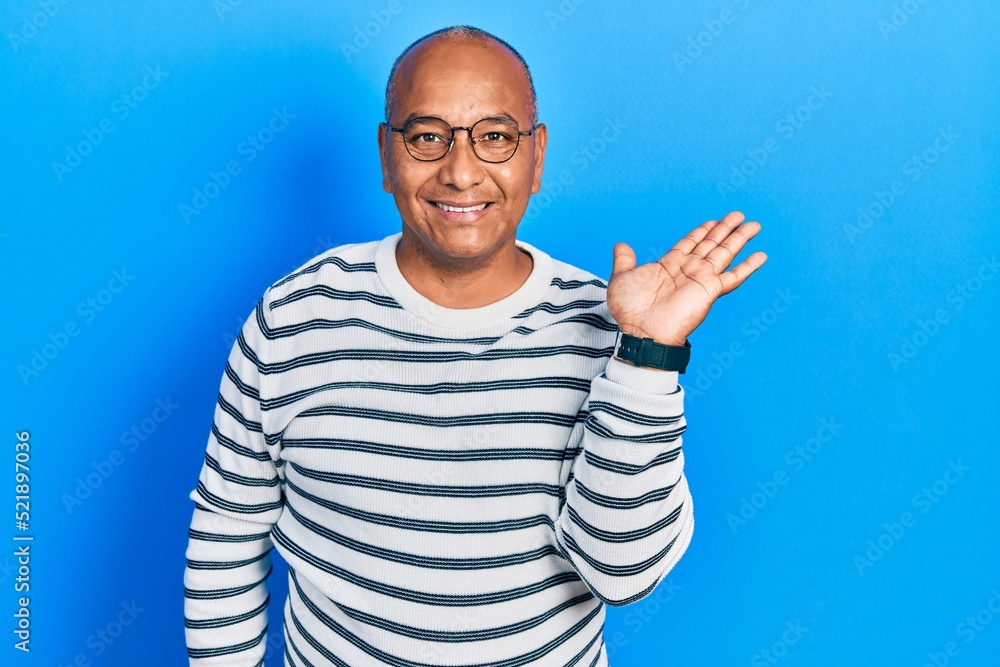 Middle age latin man wearing casual clothes and glasses smiling cheerful presenting and pointing with palm of hand looking at the camera.