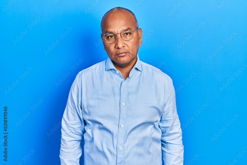 Middle age latin man wearing casual clothes and glasses relaxed with serious expression on face. simple and natural looking at the camera. Middle age latin man wearing casual clothes and glasses relaxed with serious expression on face. simple and natural looking at the camera.