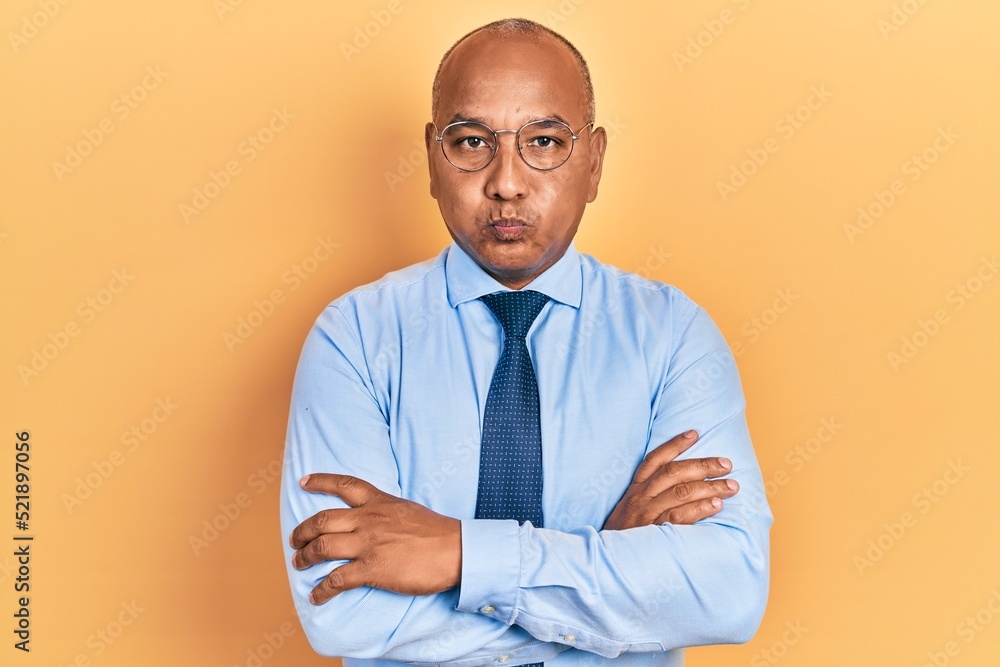 Middle age latin man wearing business clothes with arms crossed gesture puffing cheeks with funny face. mouth inflated with air, catching air. Middle age latin man wearing business clothes with arms crossed gesture puffing cheeks with funny face. mouth inflated with air, catching air.