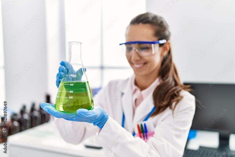 Young hispanic woman wearing scientist uniform holding test tube at laboratory Young hispanic woman wearing scientist uniform holding test tube at laboratory