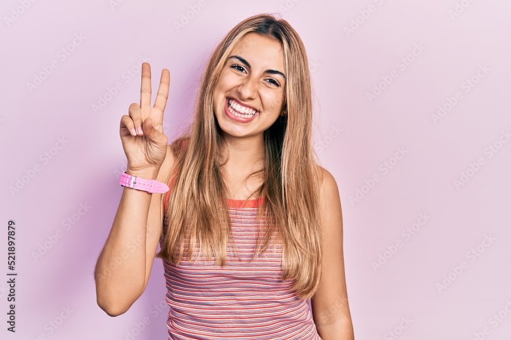 Beautiful hispanic woman wearing casual summer t shirt showing and pointing up with fingers number two while smiling confident and happy. Beautiful hispanic woman wearing casual summer t shirt showing and pointing up with fingers number two while smiling confident and happy.