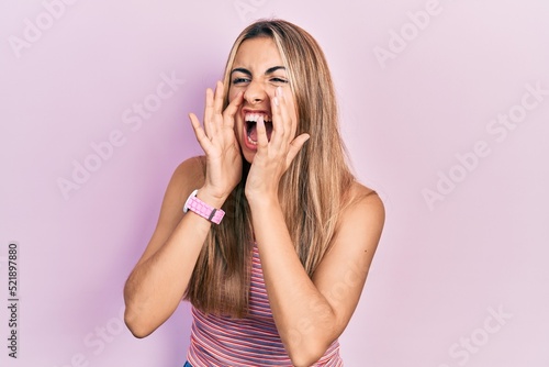 Beautiful hispanic woman wearing casual summer t shirt shouting angry out loud with hands over mouth