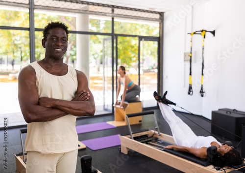 Portrait of smiling man in sportswear posing in pilates studio. Healthy lifestyle and fitness concept