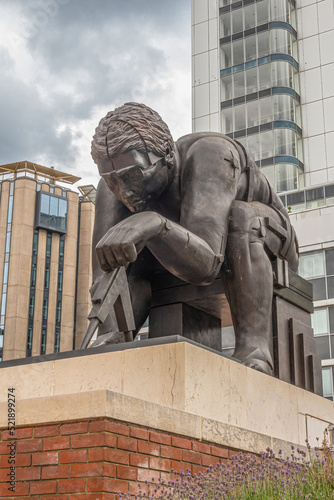 London, Great Britain - July 3, 2022: Frontal closeup of gray Newton Statue on pedestal in front yard of British Library and Knowledge Center under gray cloudscape.  photo