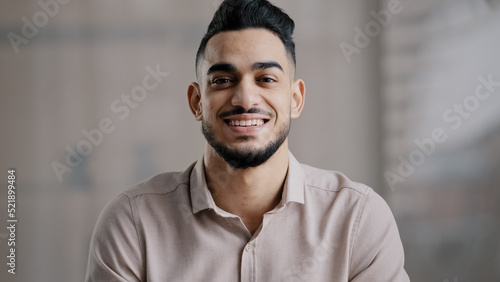 Happy joyful guy hispanic arabian handsome young man casual model with toothy smile look at camera optimistic male face portrait smiling businessman intelligent millennial posing indoors close up view