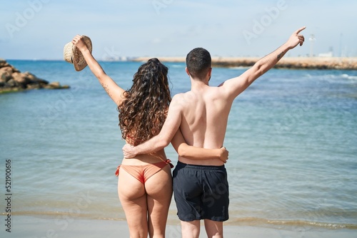 Young hispanic couple tourists wearing swimsuit hugging each other at seaside © Krakenimages.com
