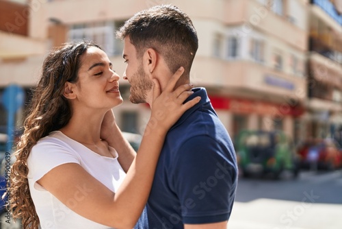 Young hispanic couple smiling confident hugging each other and kissing at street © Krakenimages.com