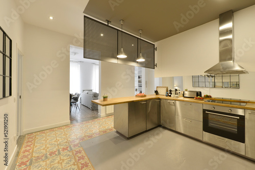 Wallpaper Mural Large open kitchen with industrial style stainless steel cabinets and appliances, wood countertops with island and gray colored floor and hydraulic tile Torontodigital.ca