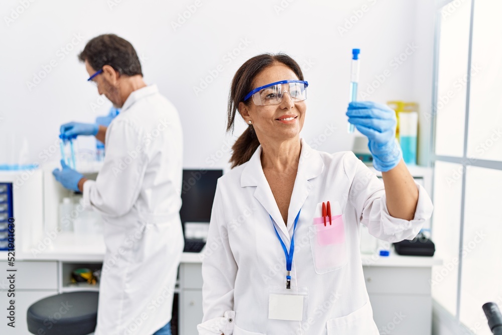 Middle age man and woman partners wearing scientist uniform holding test tube at laboratory Middle age man and woman partners wearing scientist uniform holding test tube at laboratory