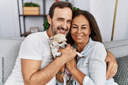 Middle age man and woman couple smiling confident sitting on sofa hugging chihuahua at home © Krakenimages.com