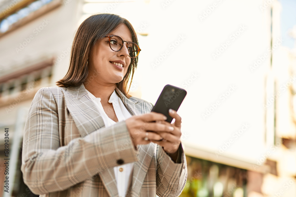 Young hispanic businesswoman smiling happy using smartphone at the city. Young hispanic businesswoman smiling happy using smartphone at the city.