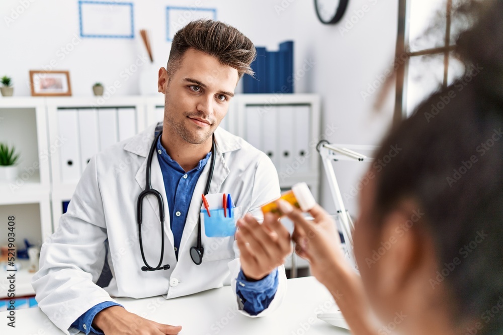 Man and woman wearing doctor uniform having medical consultation prescribe pills at clinic Man and woman wearing doctor uniform having medical consultation prescribe pills at clinic
