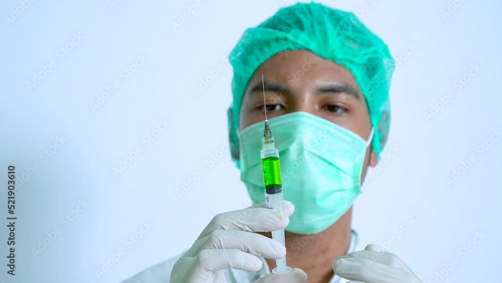 Close up male nurse checking and knocking a syringe filled with green liquid Close up male nurse checking and knocking a syringe filled with green liquid