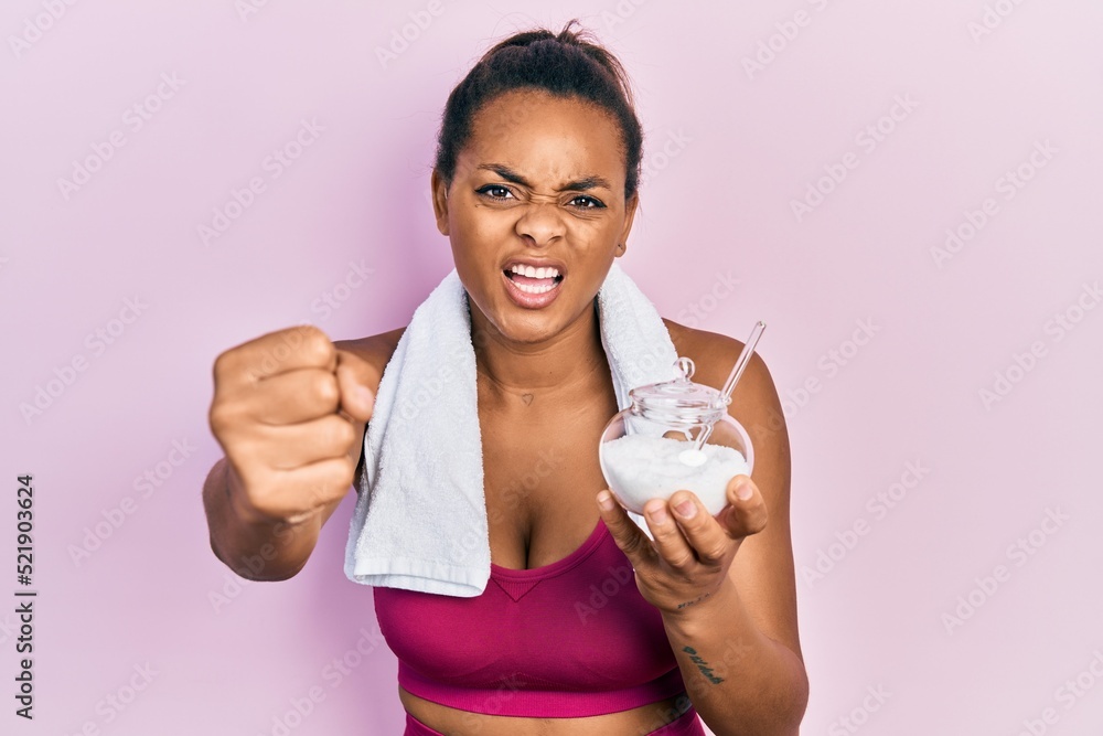 Young african american girl wearing sportswear holding sugar annoyed and frustrated shouting with anger, yelling crazy with anger and hand raised Young african american girl wearing sportswear holding sugar annoyed and frustrated shouting with anger, yelling crazy with anger and hand raised