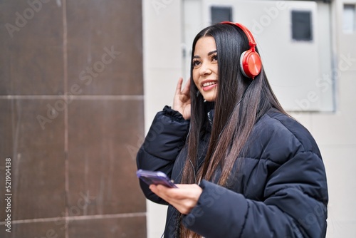 Young beautiful hispanic woman smiling confident listening to music at street
