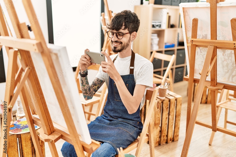 Young hispanic artist man make picture using smartphone drawing at art studio.