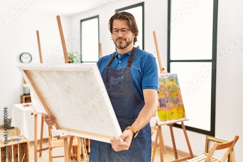 Middle age caucasian man smiling confident looking draw canvas at art studio