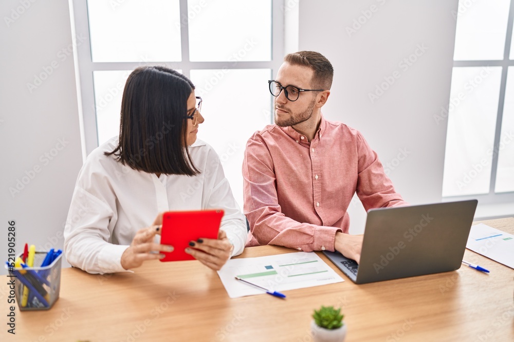 Man and woman business workers using laptop and touchpad working at office Man and woman business workers using laptop and touchpad working at office