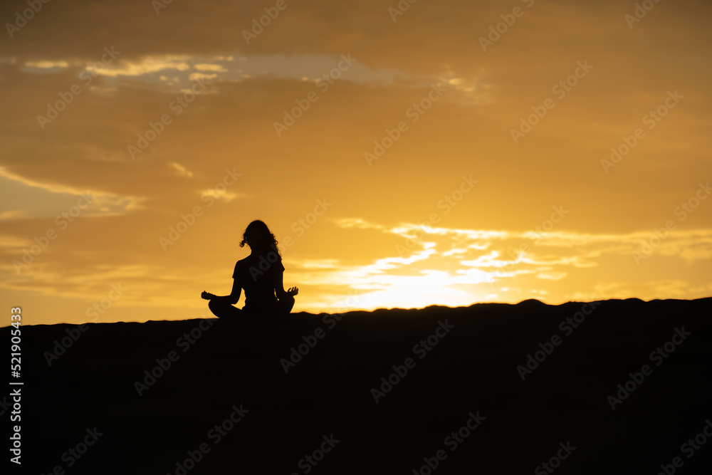 Mujer meditando a contraluz de atardecer amanecer Mujer meditando a contraluz de atardecer amanecer