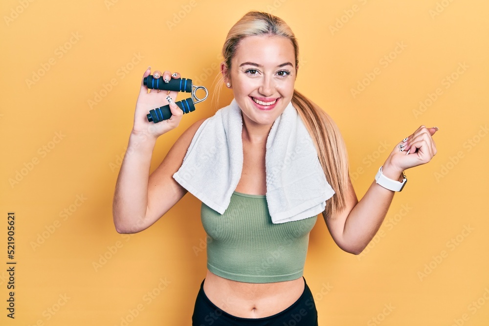 Young blonde girl training muscle with hand grip screaming proud, celebrating victory and success very excited with raised arm Young blonde girl training muscle with hand grip screaming proud, celebrating victory and success very excited with raised arm