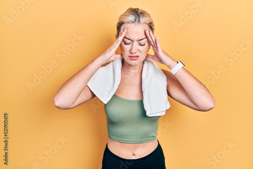 Young blonde girl wearing sportswear and towel with hand on head, headache because stress. suffering migraine. © Krakenimages.com
