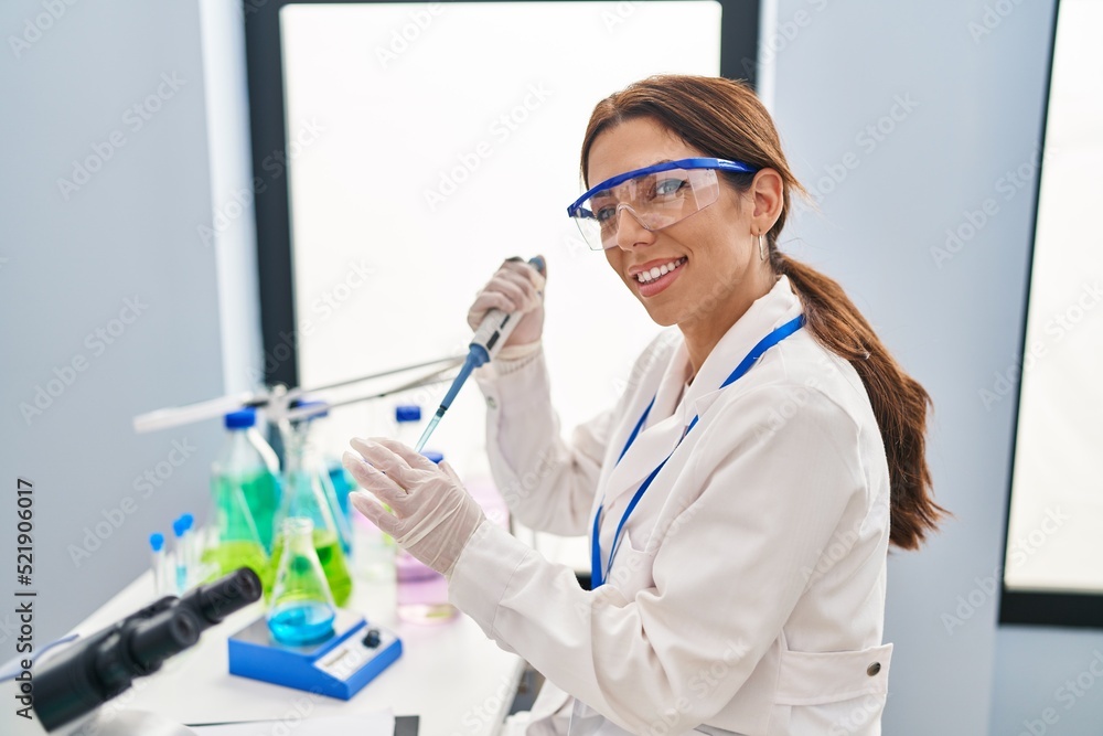 Young hispanic woman wearing scientist uniform using pipette at laboratory Young hispanic woman wearing scientist uniform using pipette at laboratory