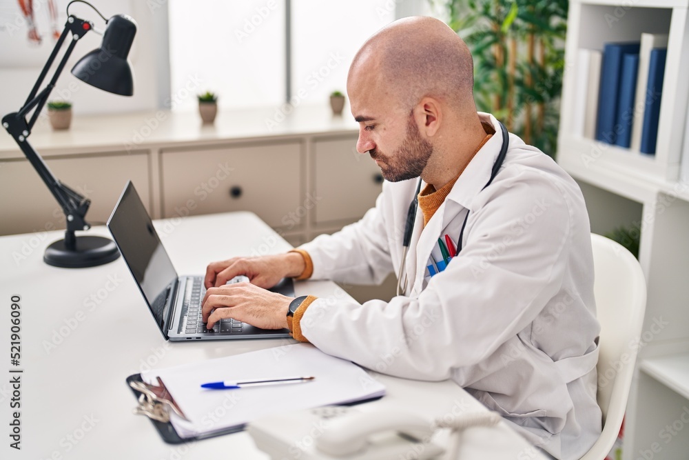Young man wearing doctor uniform using laptop at clinic Young man wearing doctor uniform using laptop at clinic