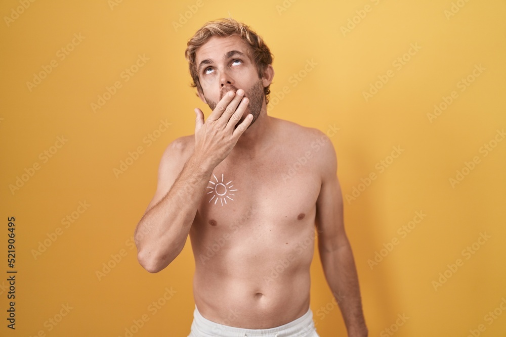 Fototapeta premium Caucasian man standing shirtless wearing sun screen bored yawning tired covering mouth with hand. restless and sleepiness.