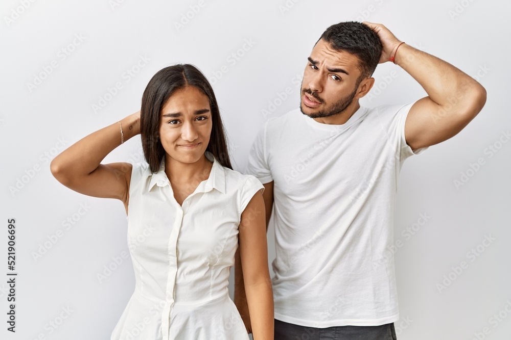 Young interracial couple standing together in love over isolated background confuse and wonder about question. uncertain with doubt, thinking with hand on head. pensive concept. Young interracial couple standing together in love over isolated background confuse and wonder about question. uncertain with doubt, thinking with hand on head. pensive concept.