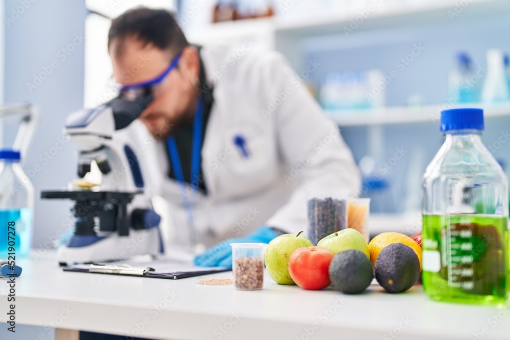 Young hispanic man scientist write on report using microscope at laboratory Young hispanic man scientist write on report using microscope at laboratory