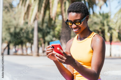 trendy african american woman online shopping with credit card and smart phone in the street. photo