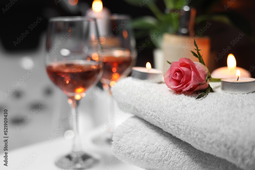 Rose and burning candle on towel near glasses of wine, closeup. Romantic bath Rose and burning candle on towel near glasses of wine, closeup. Romantic bath