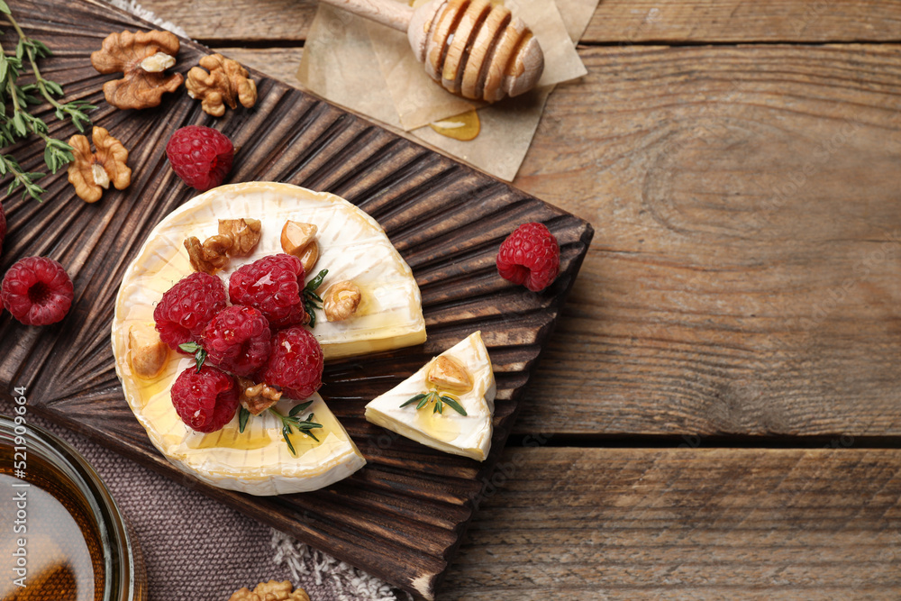 Brie cheese served with raspberries, walnuts and honey on wooden table, flat lay. Space for text Brie cheese served with raspberries, walnuts and honey on wooden table, flat lay. Space for text