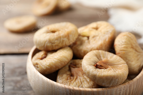 Tasty dried figs in bowl on wooden table, closeup