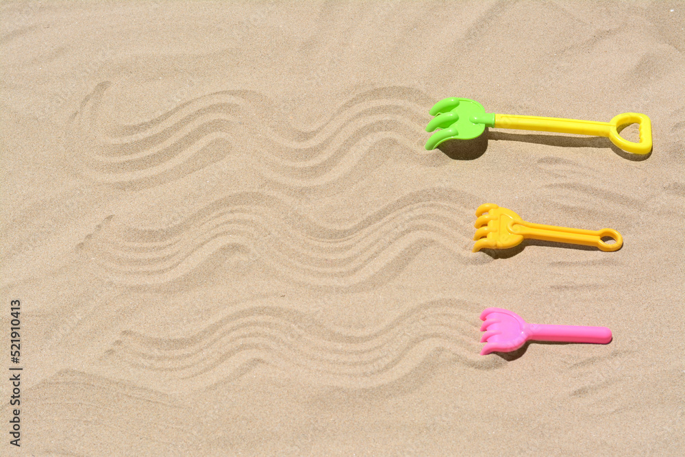 Plastic rakes on sand, space for text. Beach toys Plastic rakes on sand, space for text. Beach toys