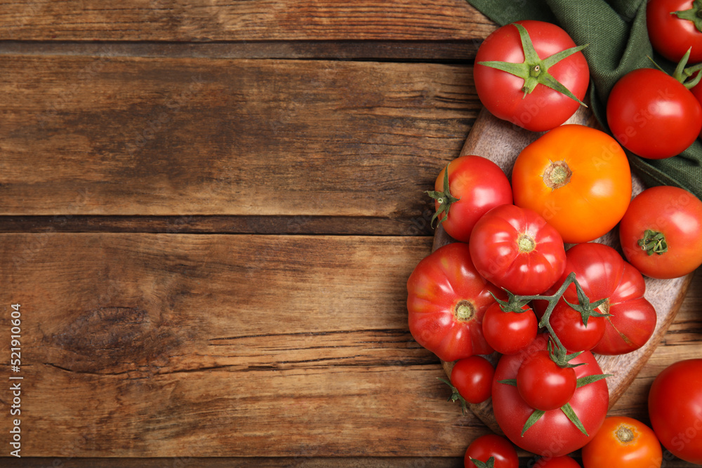 Many different ripe tomatoes on wooden table, flat lay. Space for text Many different ripe tomatoes on wooden table, flat lay. Space for text