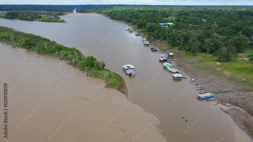 Aerial view moving forward shot, Boat docks on the shore of the amazon river in Colombia. Brown and polluted amazon river below. Environmental Catastrophe concept. Aerial view moving forward shot, Boat docks on the shore of the amazon river in Colombia. Brown and polluted amazon river below. Environmental Catastrophe concept.