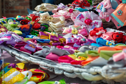 Orlando, Florida, US-July 2022: A table at a bazaar covered in headbands, colorful hairpins, and ribbon bows. The handmade fabric ponytail ribbons are stylish textile trinkets. 