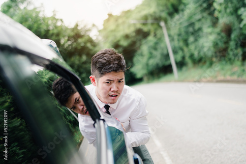 Asian businessman pushing broken down car on the mountain road, Emergency call concept. © Kiattisak