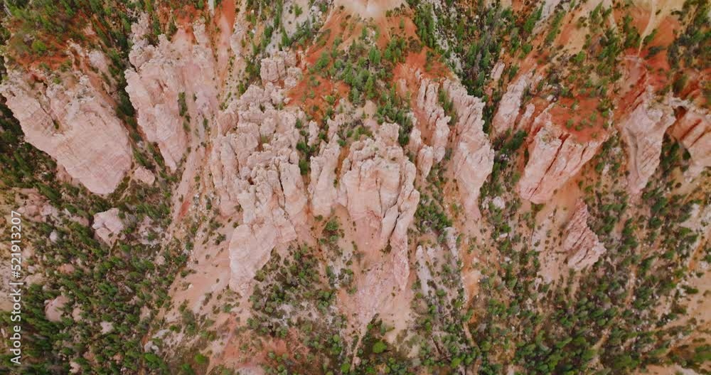 Slow descending over the tremendous rocks of Bryce Canyons in Utah, United States. Little pine trees grooving on the slopes of wonderful landscape. Top view. Slow descending over the tremendous rocks of Bryce Canyons in Utah, United States. Little pine trees grooving on the slopes of wonderful landscape. Top view.