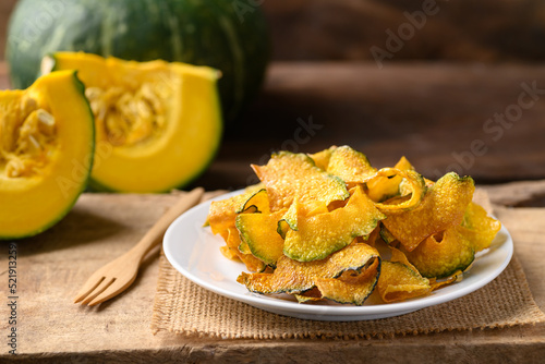 Pumpkin chips on plate with wooden background, Healthy vegan snack