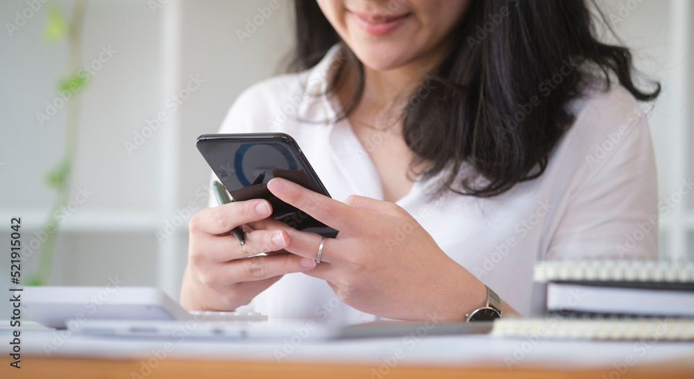 Young woman sitting in bright office and using smart phone for internet banking online or communicating on social network. Young woman sitting in bright office and using smart phone for internet banking online or communicating on social network.