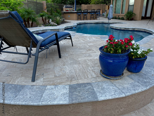 Obraz na plátně A travertine tiled pool deck with a spa and outdoor kitchen on a desert landscaped backyard in Arizona