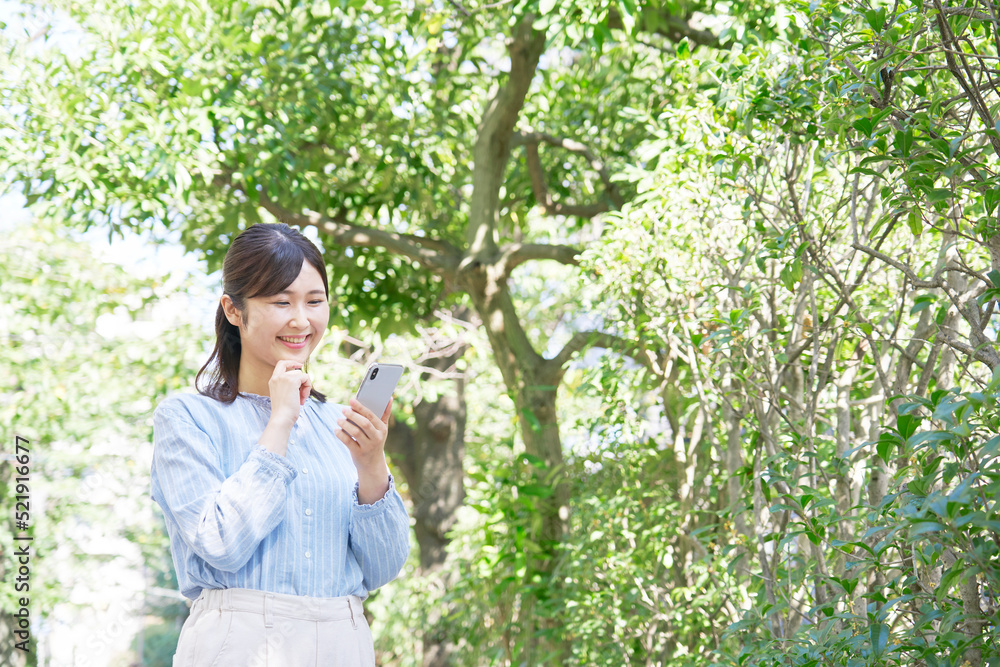 屋外で笑顔でスマホを使う女性 屋外で笑顔でスマホを使う女性