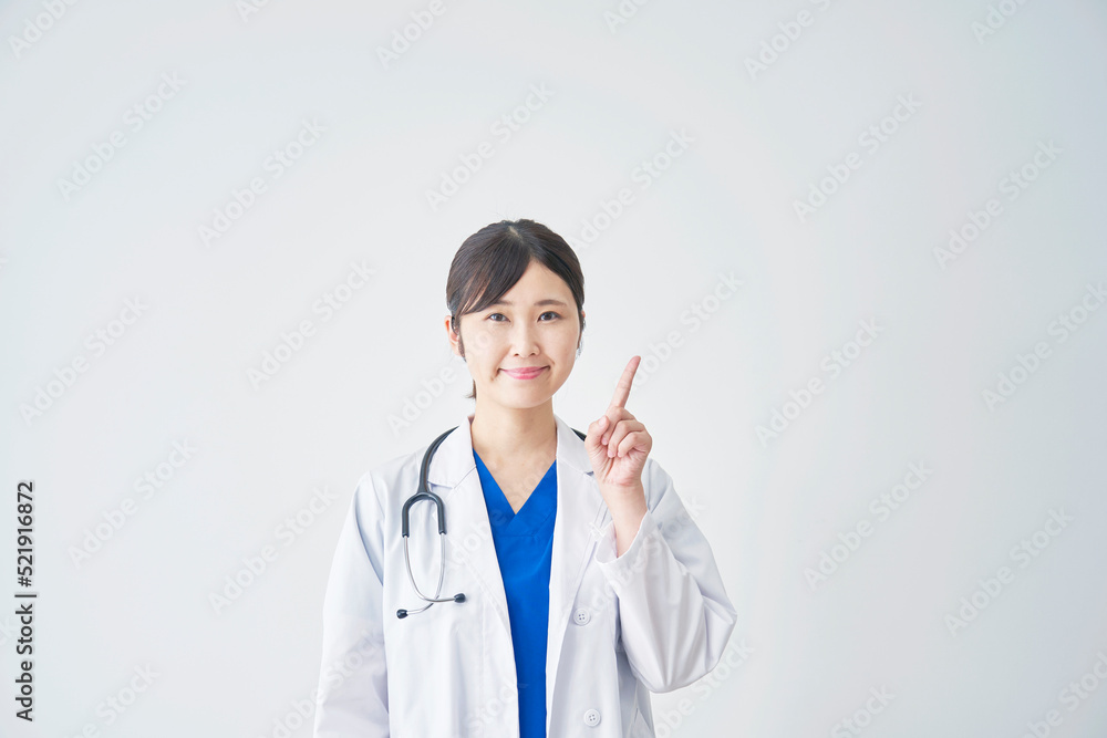 白バックで右を指差す女性医師　コピースペースあり