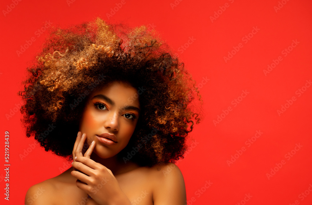 Fototapeta premium Young beautiful african american woman with afro hair. Glamour makeup. Red Background.