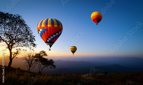 Colorful hot air balloons flying over mountain at sunset. adventure in summer vacation. © jakkapan