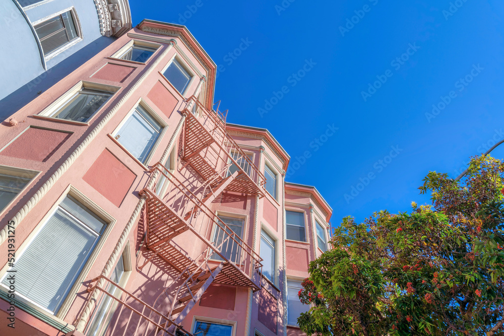 Low angle view of a pink apartment building with emergency staircase in the middle