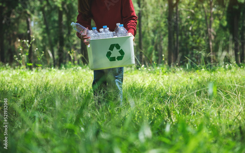 Closeup of a woman collecting garbage plastic bottles into a recycle bin in the outdoors