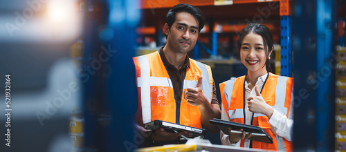 Warehouse worker and manager using digital tablet doing happy thumbs up gesture with hand. . Approving expression looking at the camera with showing success. Warehouse, import and Export Concept.